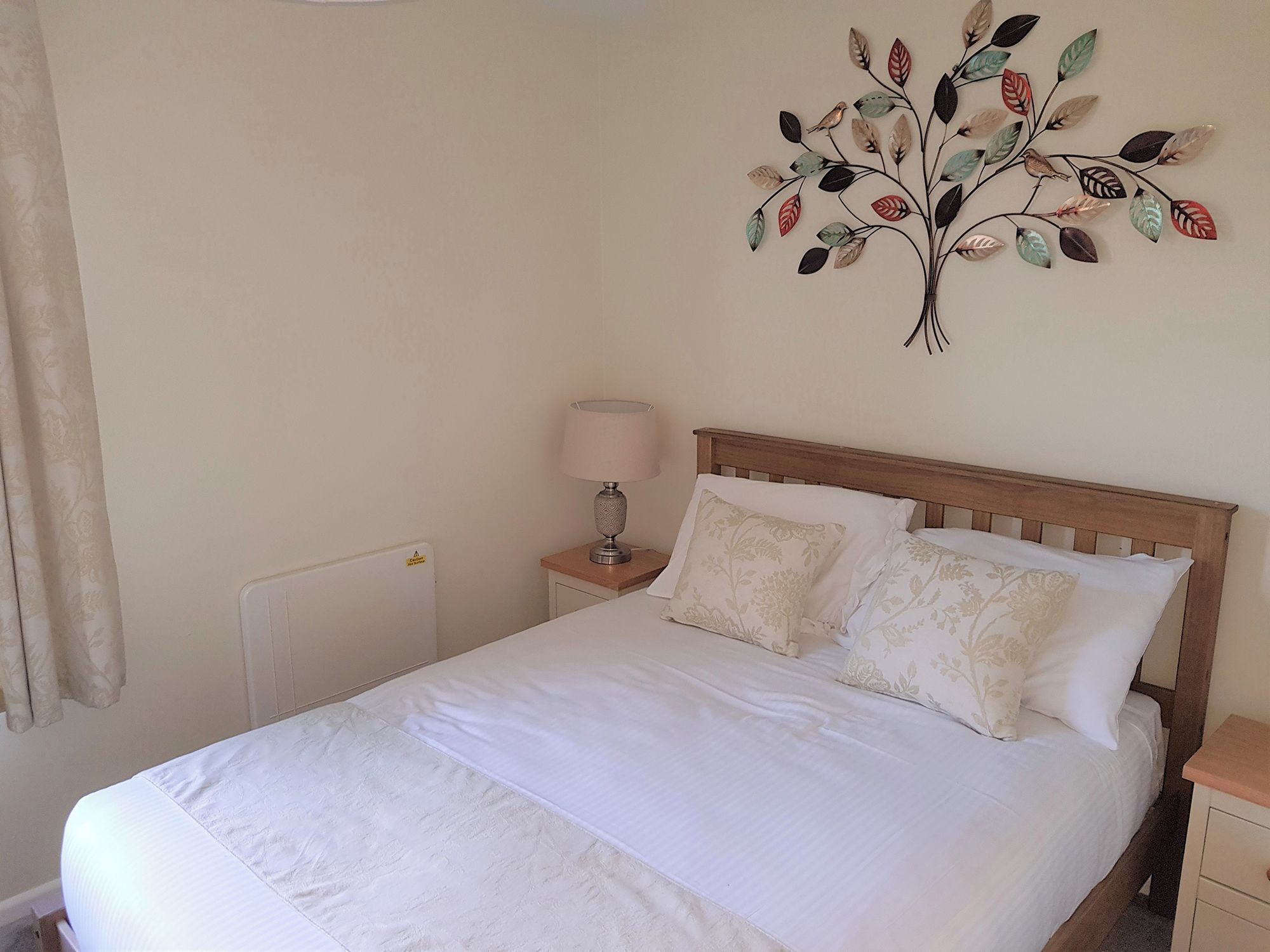 Un lit bien fait, avec du linge de lit blanc, dans une pièce au design simple et épuré.