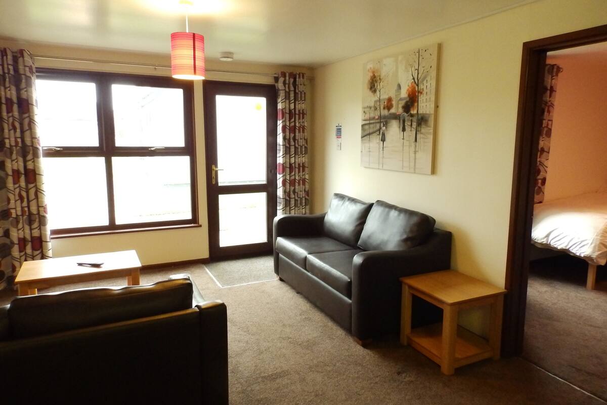 Ein Wohnzimmer mit einer Ledersofa, einem kleinen Holztisch und einem Bild an der Wand.
