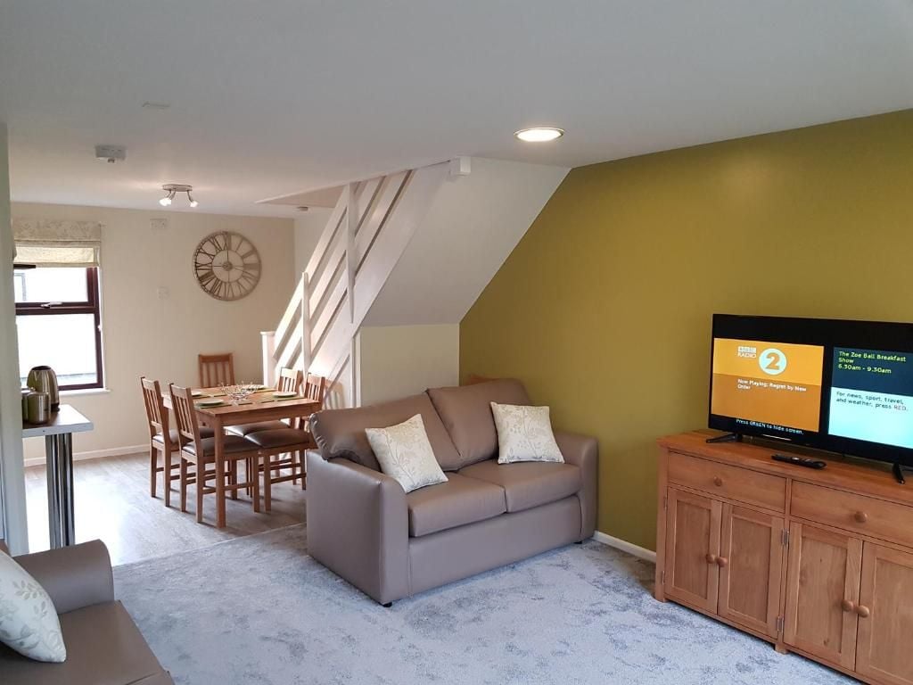 A living room with a sofa, dining table, and a television on a cabinet.