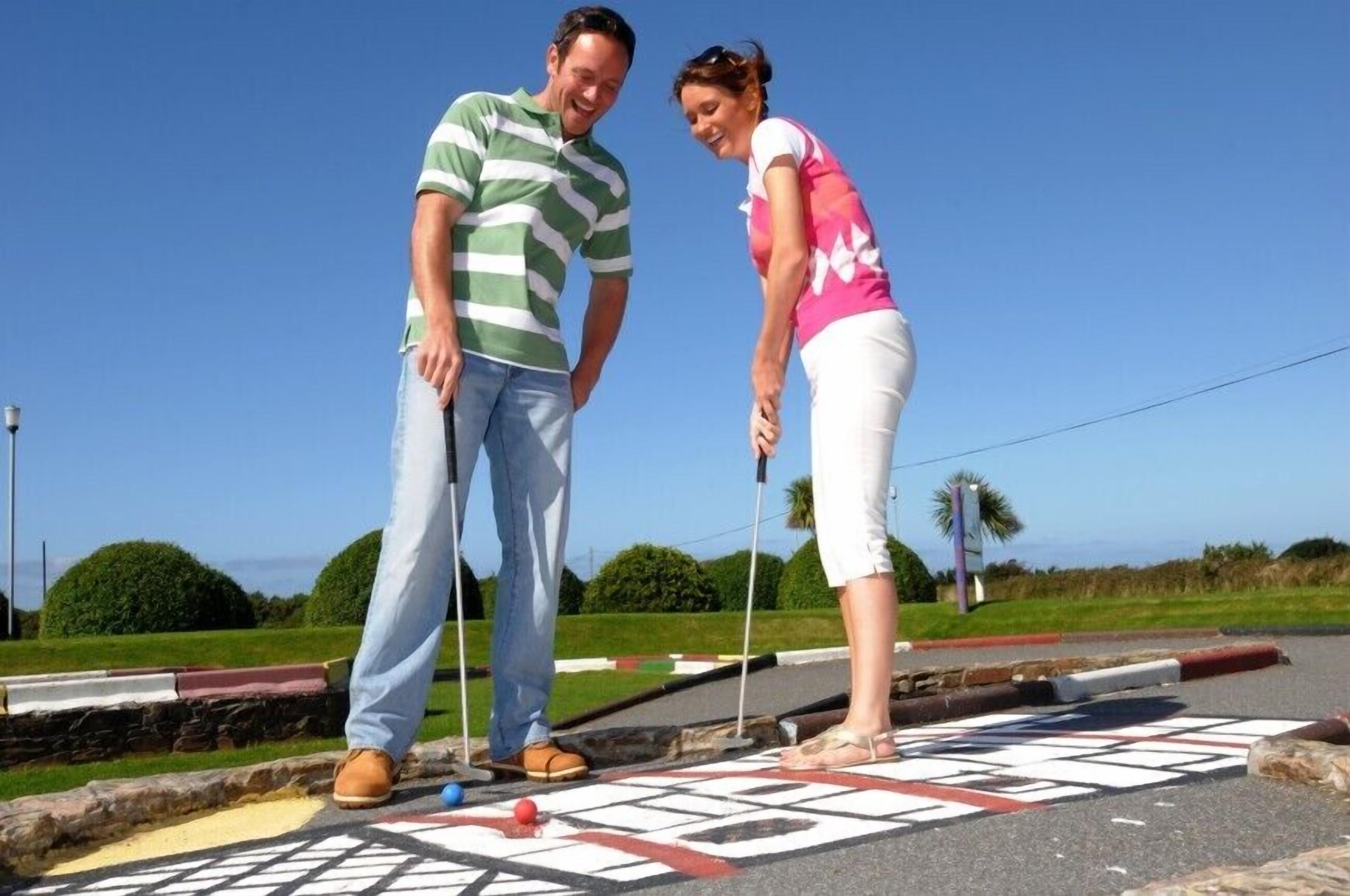 Two people playing a lawn game on a paved area with a geometric pattern.