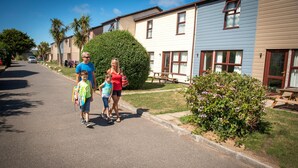 A residential street with houses, a clear sky, and a family walking. - Perran View Holiday Park (St. Agnes)
