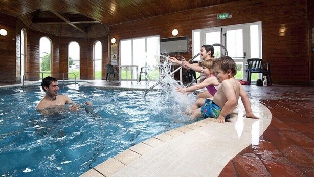 An indoor swimming pool with wooden walls and large windows. - Perran View Holiday Park (St. Agnes)