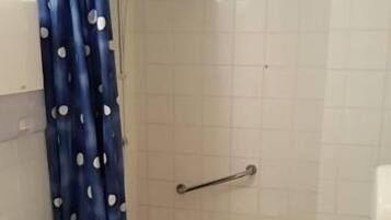 A bathroom with a toilet, shower, and sink.