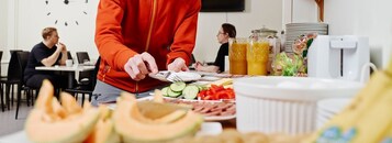 En frukostbuffé med ett urval av olika frukter och grönsaker, en kaffemaskin och juiceautomater.