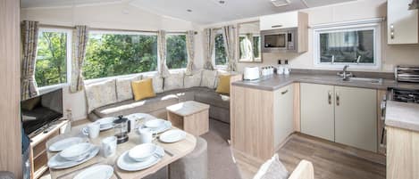 A compact, modern kitchen with a dining area, built-in appliances, and large windows.
