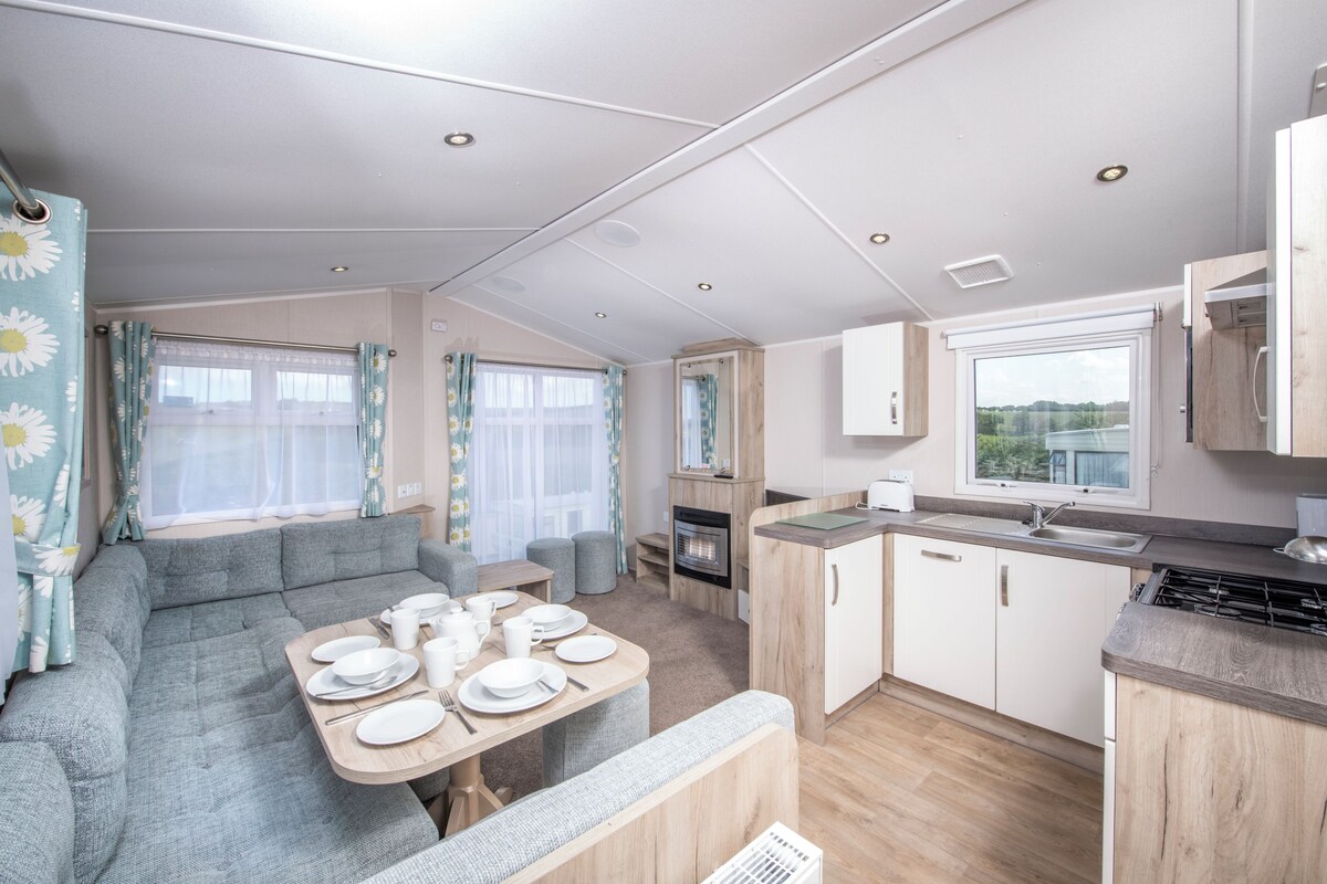 A caravan interior with a dining area, kitchenette, and seating space.