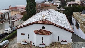 A white building with a tiled roof, surrounded by a cobblestone street and other buildings. - Epic Rooms (Delphi)