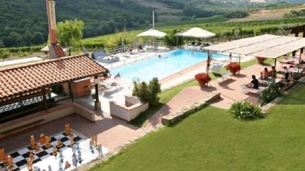 A pool area with lounge chairs and umbrellas, surrounded by a landscaped garden and a view of rolling hills. - Borgo Filicardo (Montespertoli)