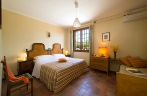 Et hotelværelse med seng, sengeborde, en stol, et skrivebord, en lampe og et vindue med gardiner.