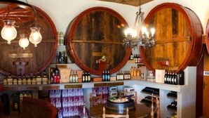 A bar area with wooden barrel-shaped shelves, a round wooden table, and several chairs. - Borgo Filicardo (Montespertoli)