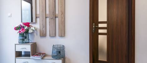 A wooden door, a white console with drawers, a mirror, and a vase with flowers.