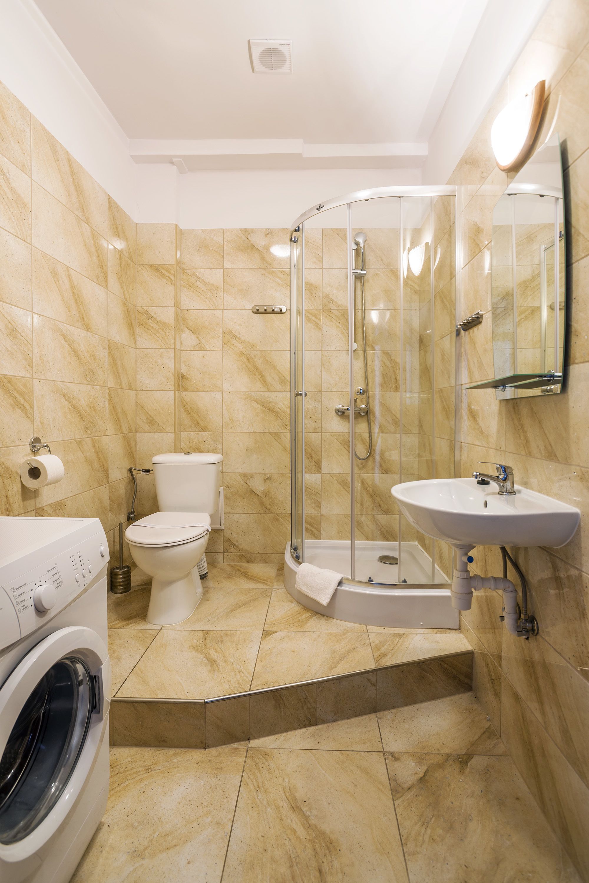 Un baño con ducha acristalada, inodoro, lavabo y lavadora.