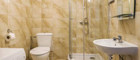 Un baño con ducha acristalada, inodoro, lavabo y lavadora.