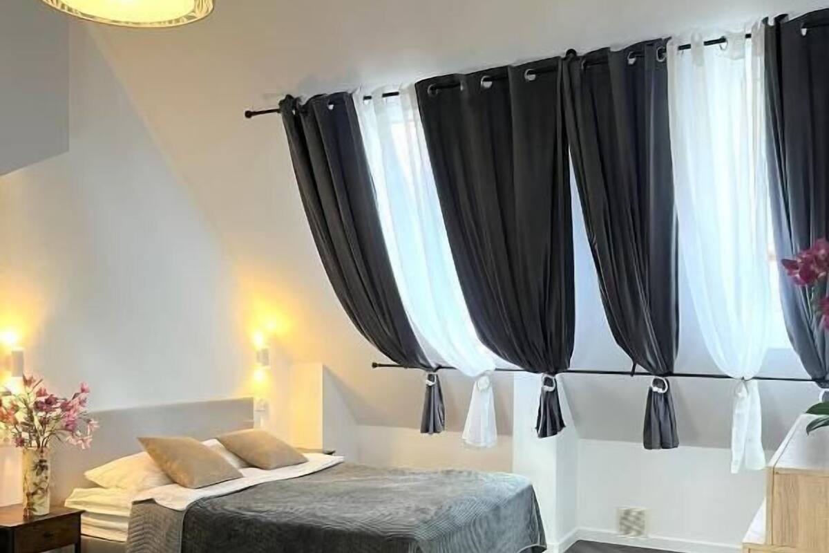 A modern bedroom with a bed, bedside tables, a lamp, and a sofa.
