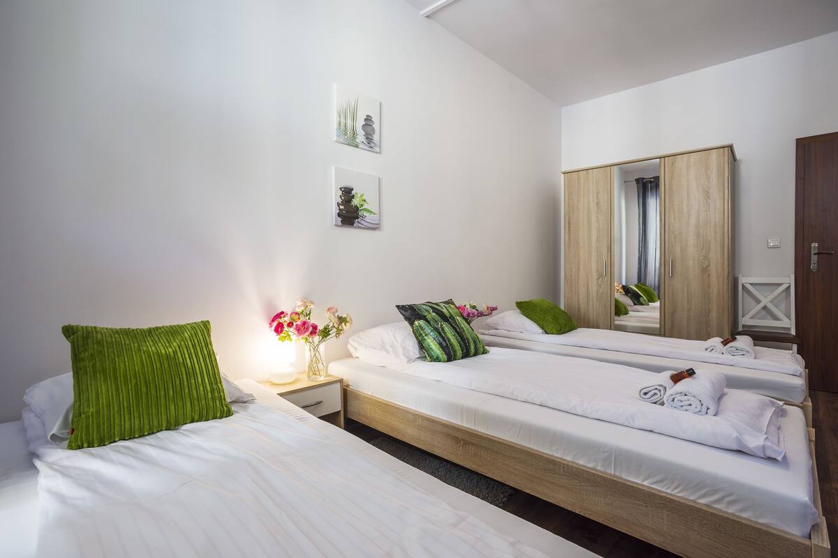 A hotel room with two beds, a wooden wardrobe, a mirror, and artwork on the wall.