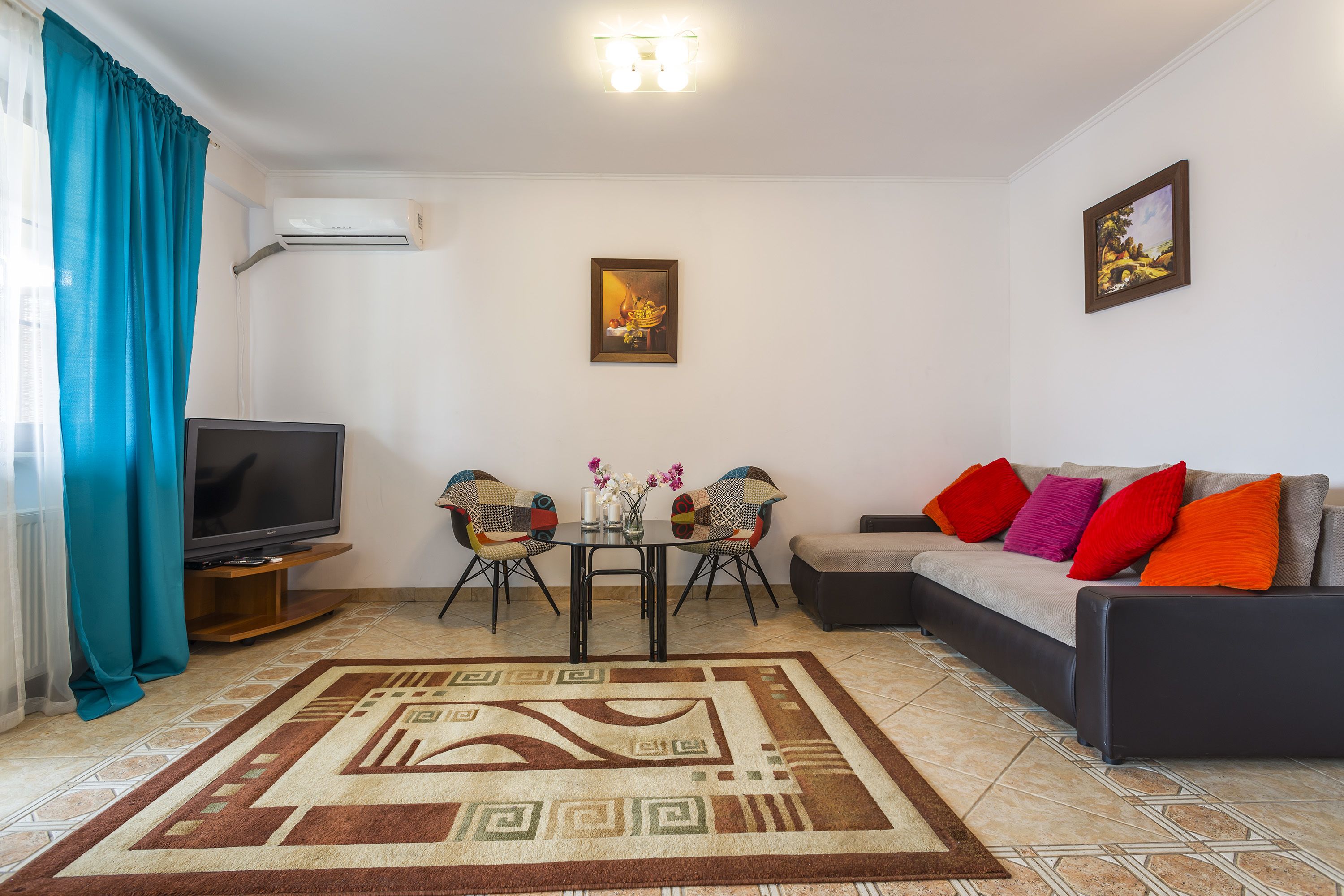 Una sala de estar con sofá, televisión y una mesa de comedor con sillas.