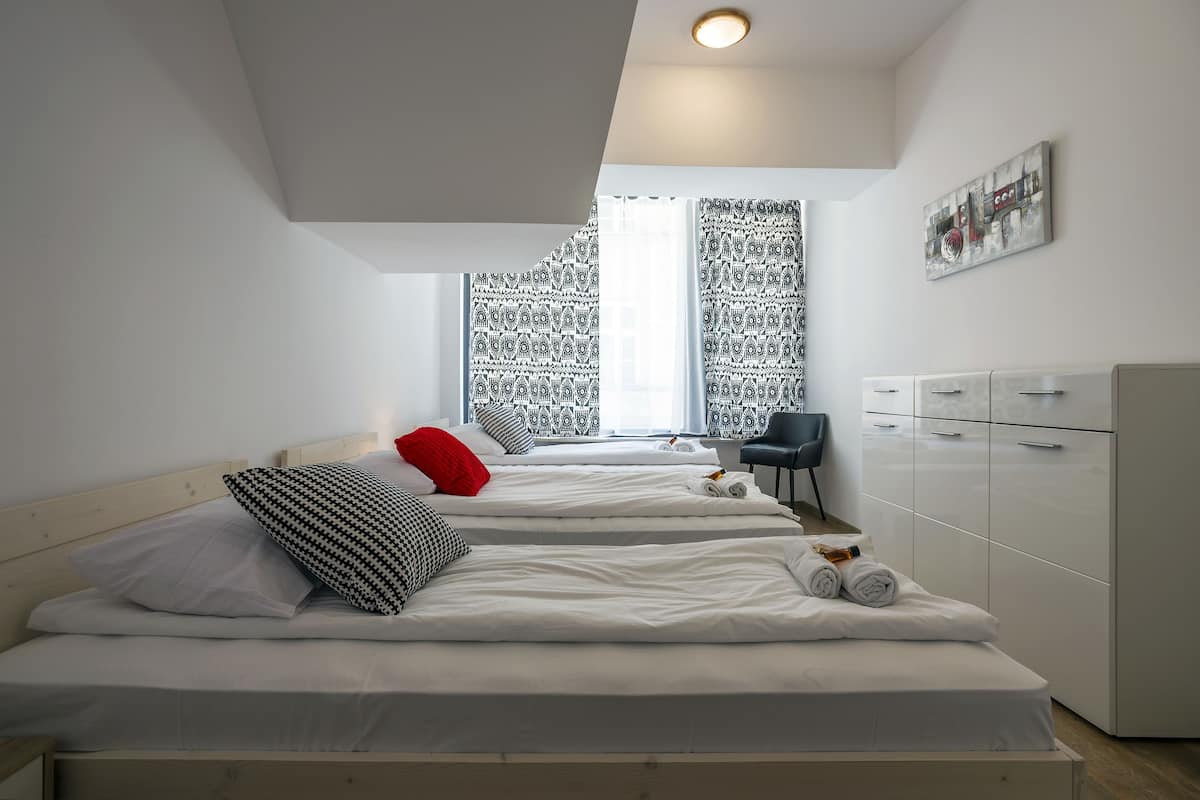 A modern bedroom with two beds, a desk, and a wardrobe.