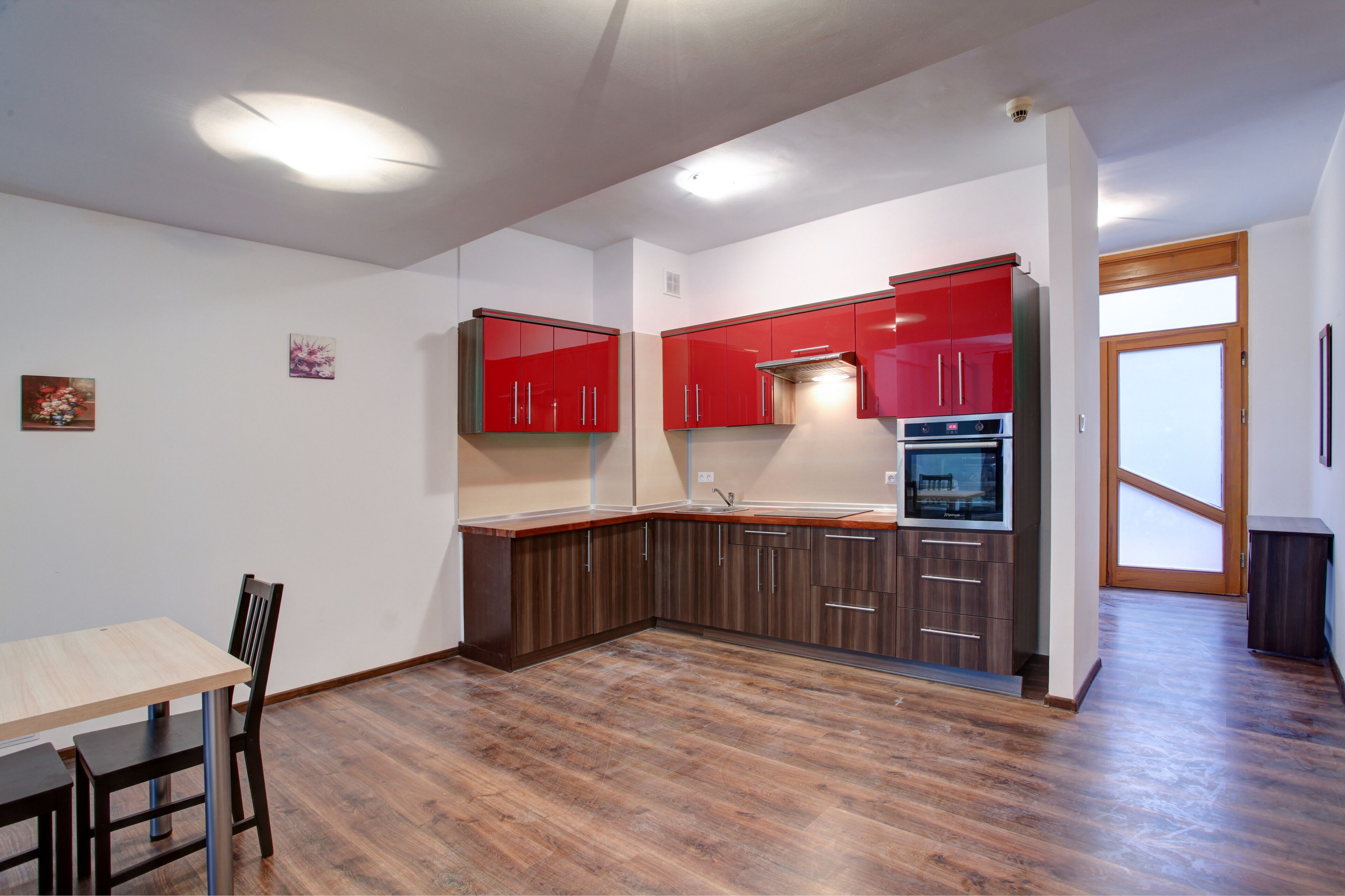 Una cocina moderna con armarios rojos, encimera de madera y un comedor con mesa y sillas.