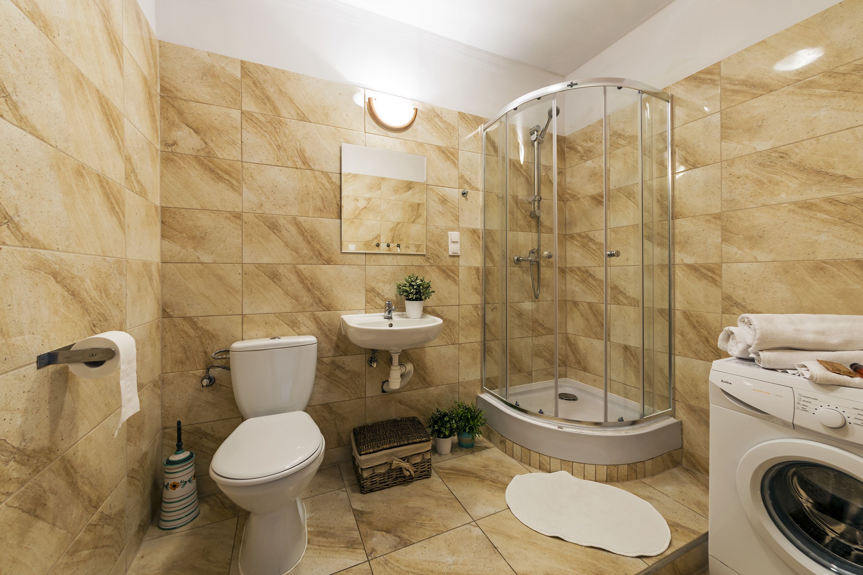 A bathroom with a toilet, sink, shower, and washing machine.