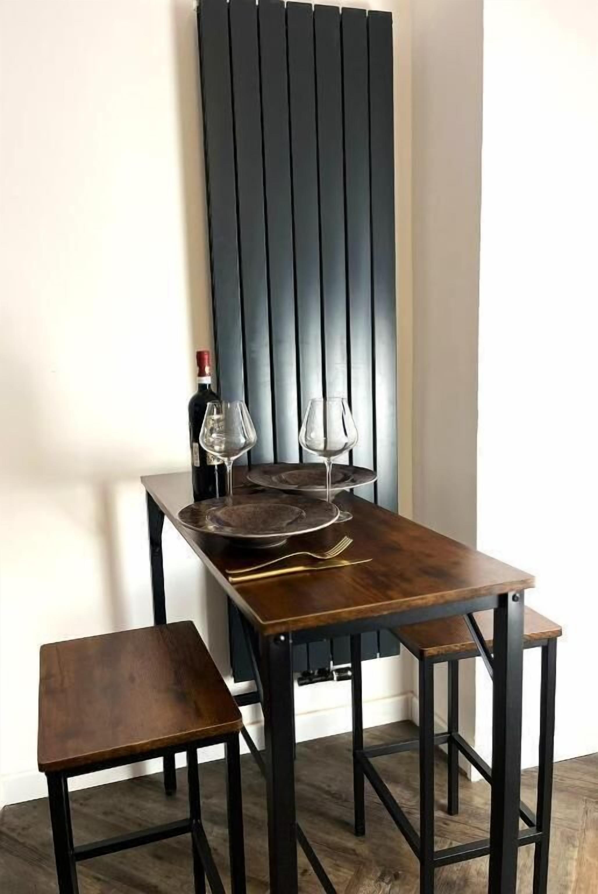 A dining table with a wine bottle and glasses, accompanied by a bench and stools.