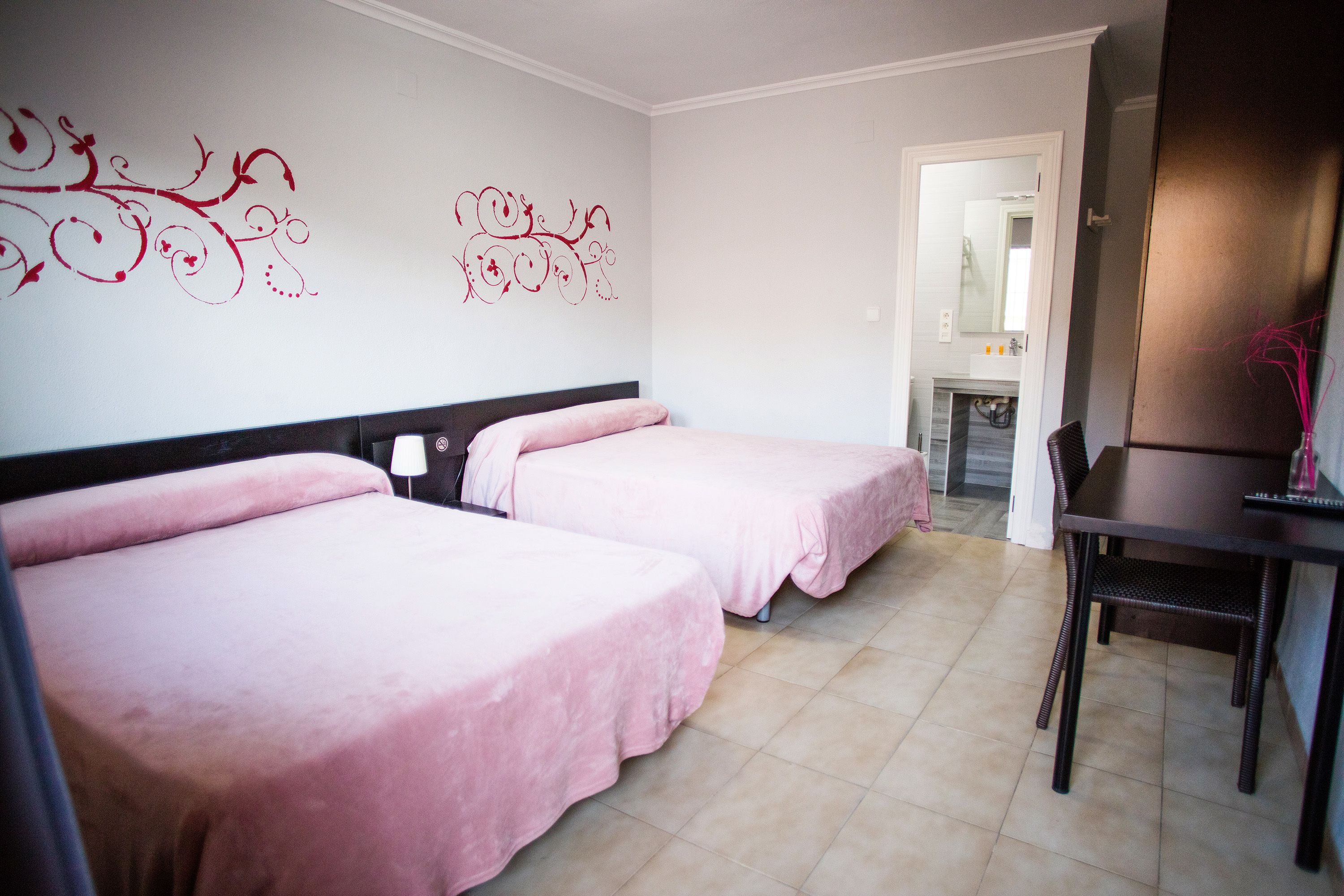 Quarto de hotel com duas camas, uma escrivaninha e uma cadeira.