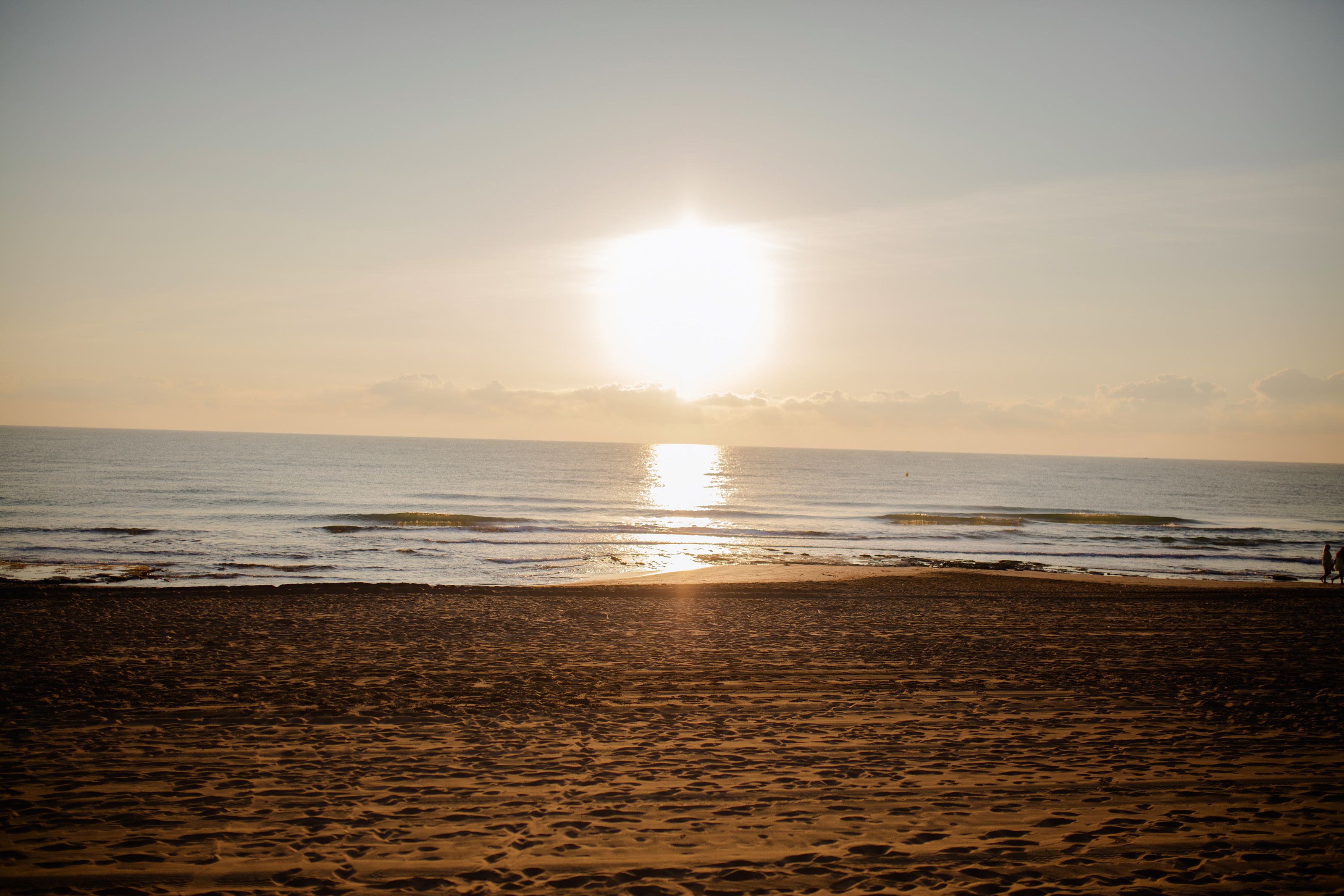 Een strand met de ondergaande zon aan de horizon.