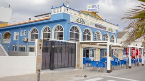 Un edificio azul con un letrero que dice "ALBA RESTAURANTE" y una entrada con reja.