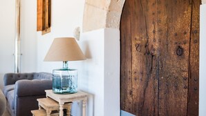 A room with a wooden door, a lamp on a small table, and a sofa. - Agroturismo Ses Vistes (Porreres)