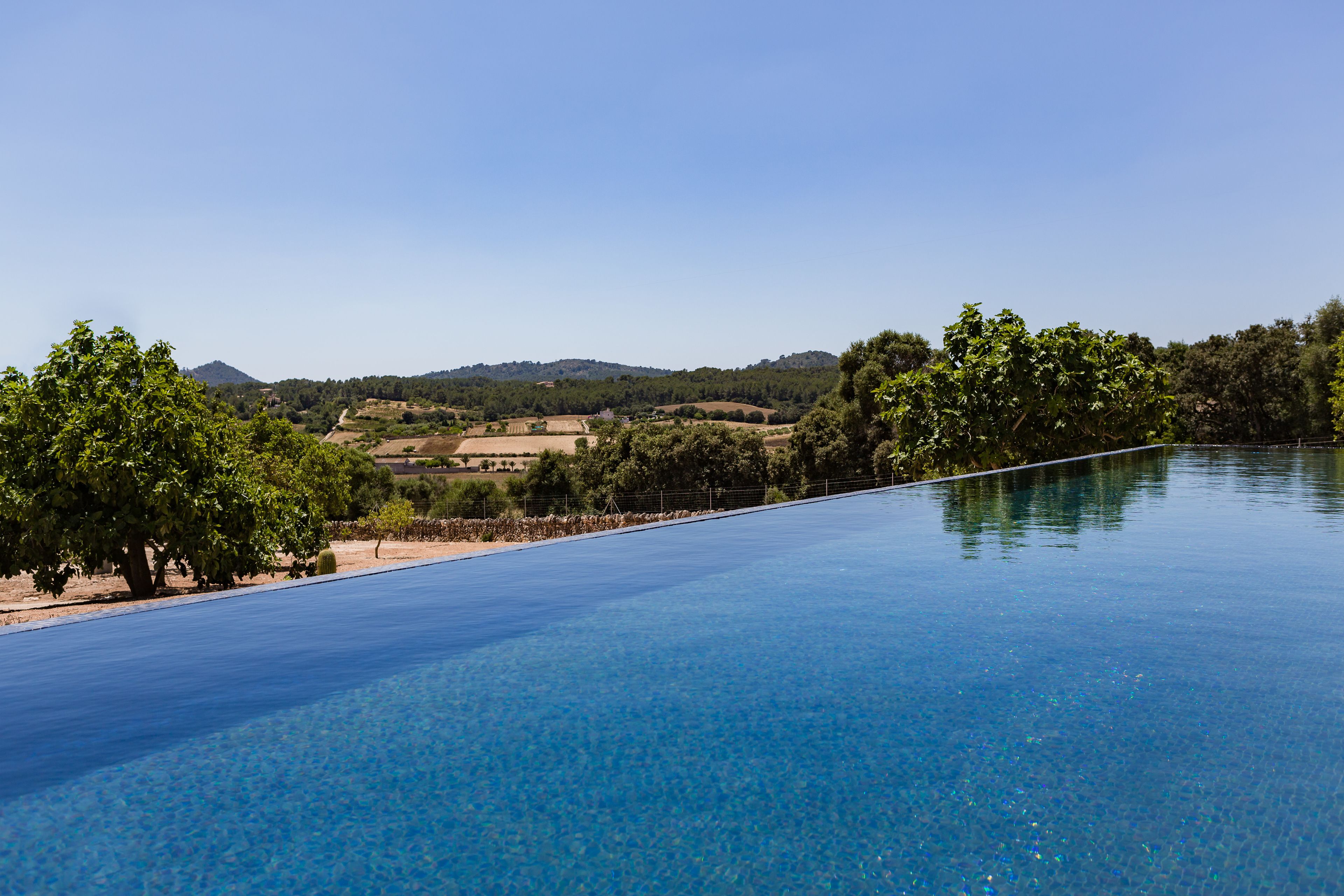 Uma piscina infinita azul límpida com vista para uma paisagem arborizada e montanhosa.