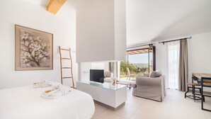 A modern hotel room with a bed, a glass-top desk, a TV, and a view of the outdoors. - Agroturismo Ses Vistes (Porreres)