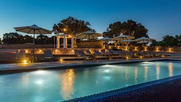 Een buitenzwembad, een infinitypool en ligstoelen