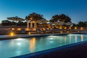 Una piscina al aire libre, una piscina con borde infinito, tumbonas