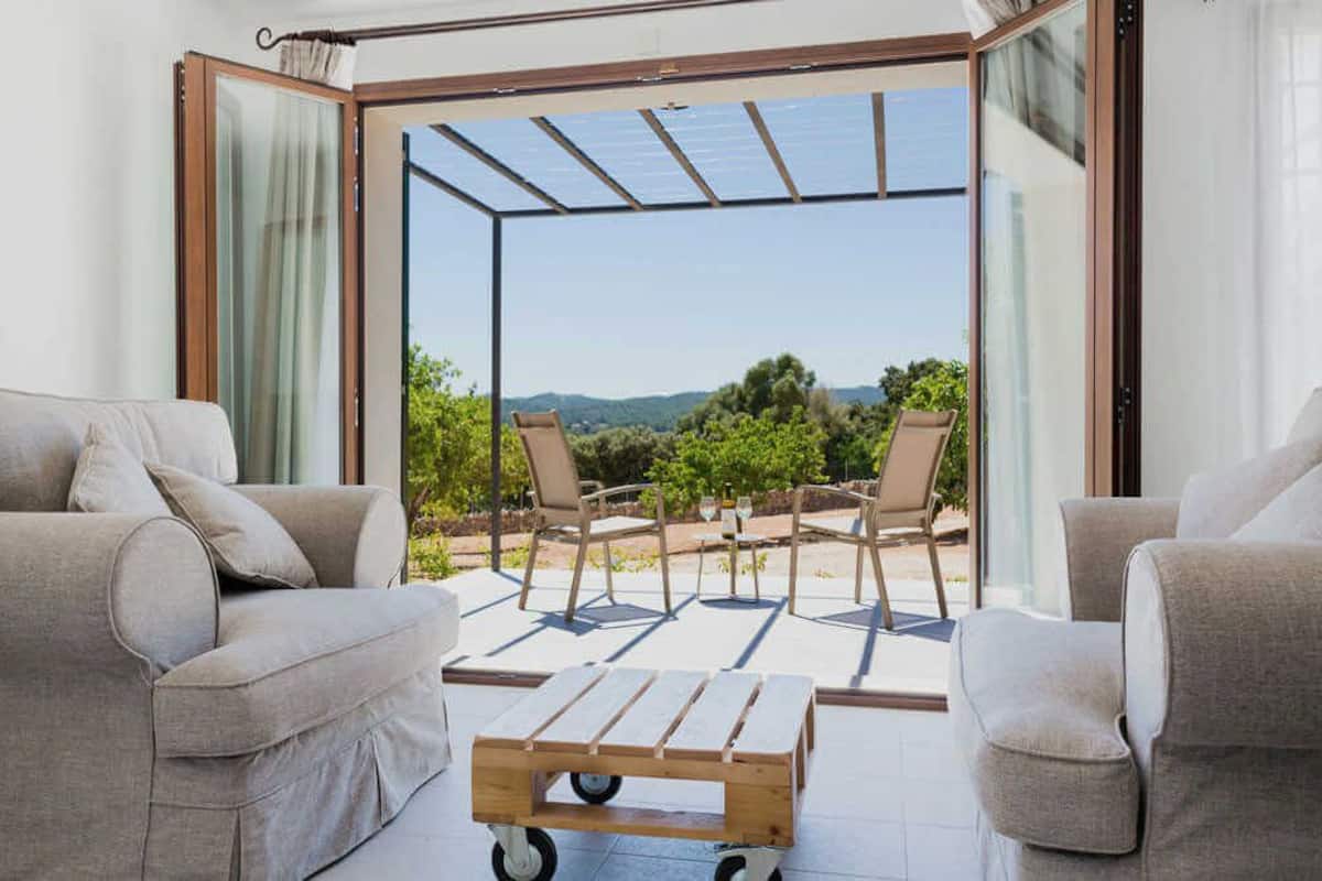 Een moderne woonkamer met een glazen deur die leidt naar een balkon met tuinmeubilair en een prachtig uitzicht.