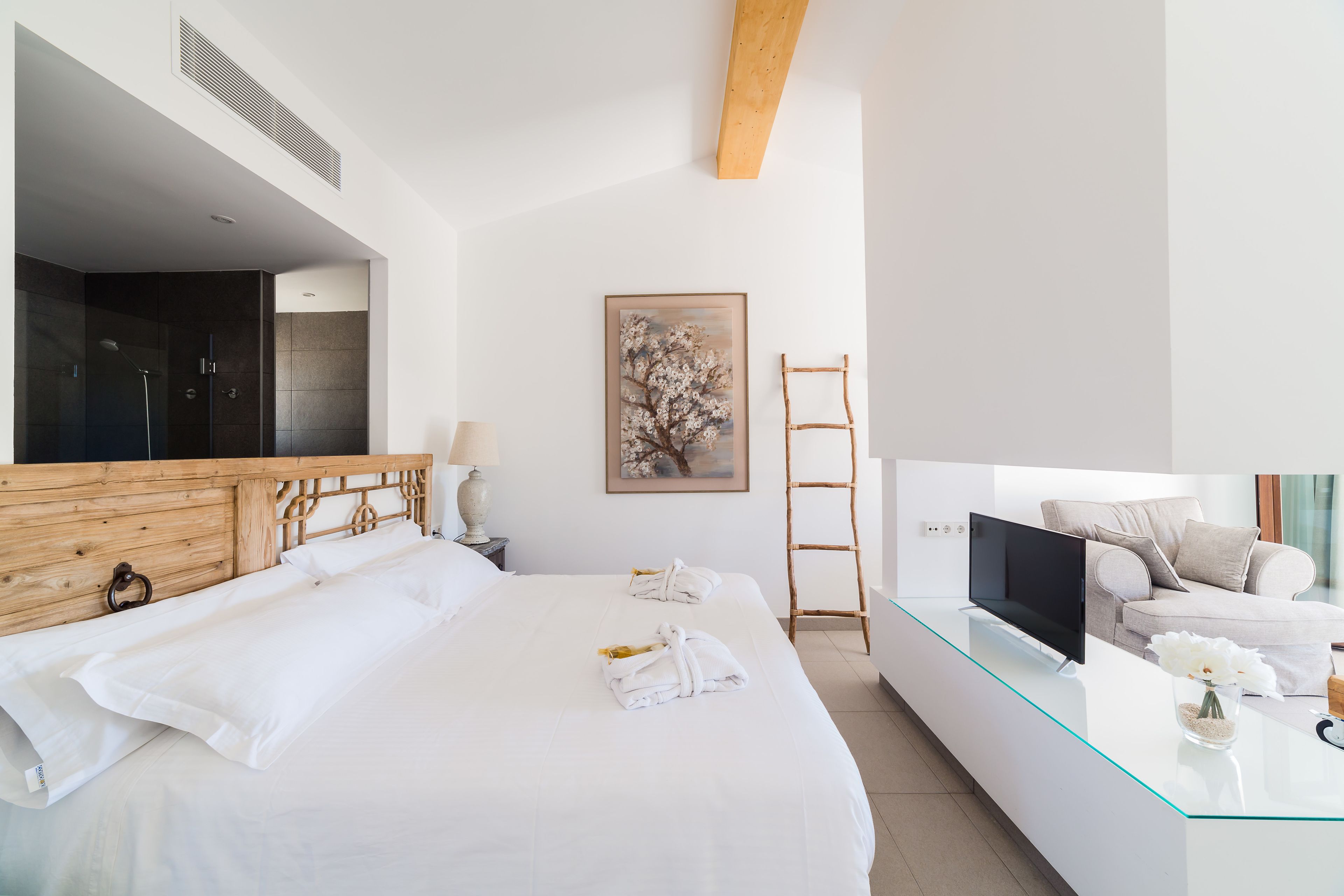 Une chambre d’hôtel moderne avec un grand lit, un bureau en verre, une télévision et un tableau au mur.