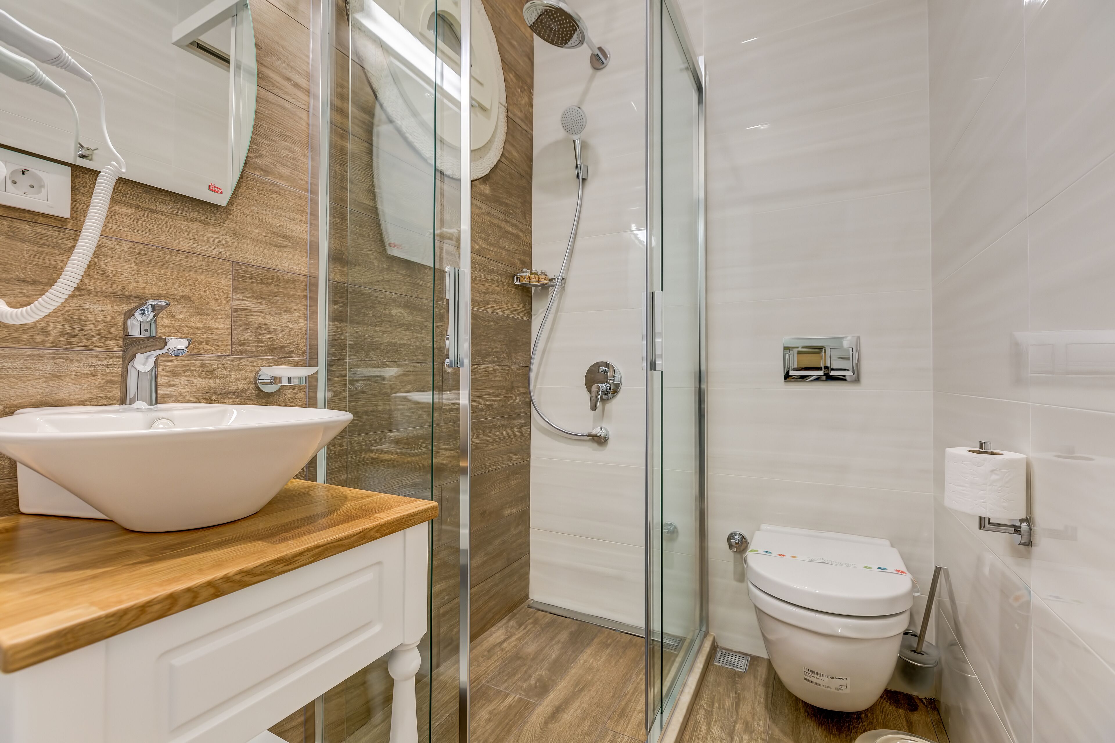 A modern bathroom with a glass shower enclosure, a white sink, and a toilet.