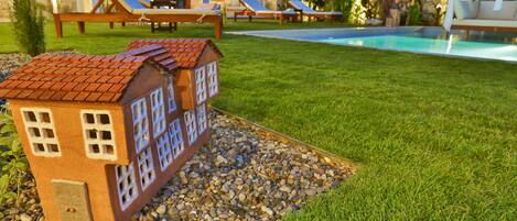 Una casa model amb teulada de rajola i nombroses finestres, envoltada d'una zona verda i una piscina.