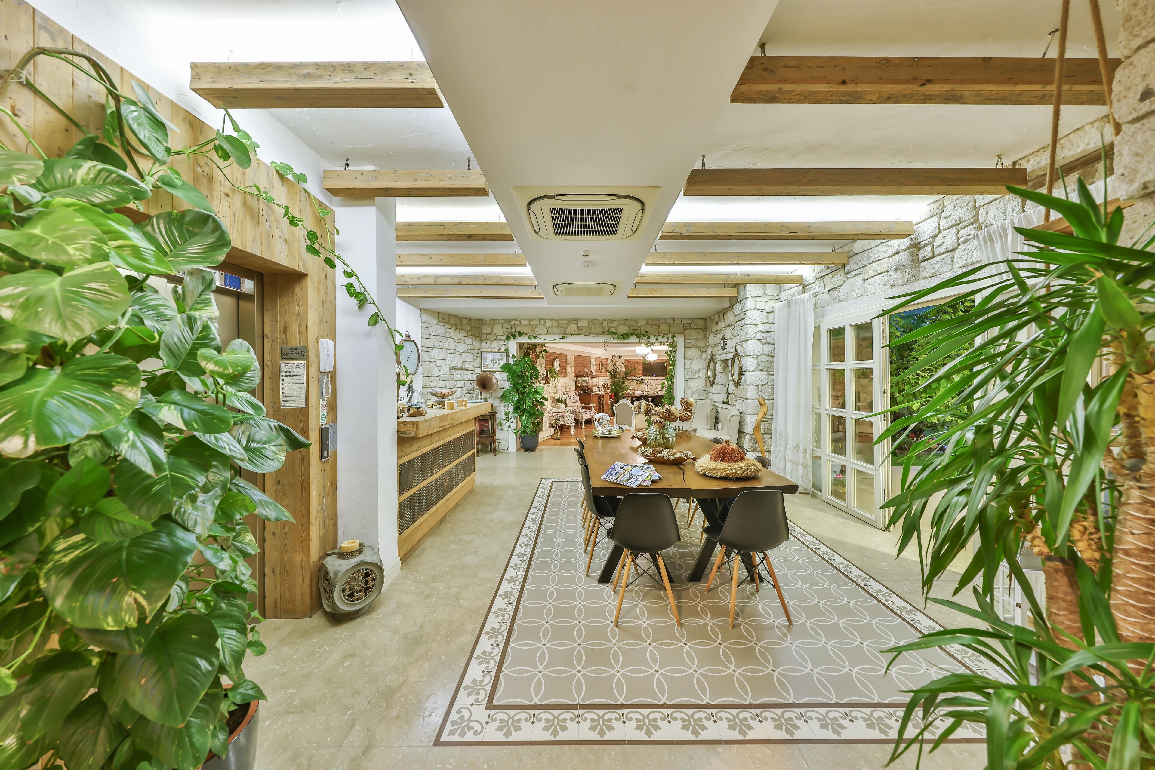 Un coin repas accueillant, avec une table et des chaises en bois, entouré de plantes en pot.