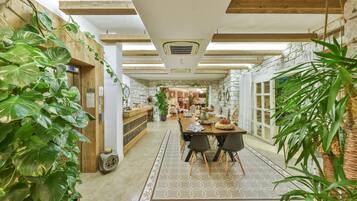 A cozy dining area with a wooden table and chairs, surrounded by potted plants.