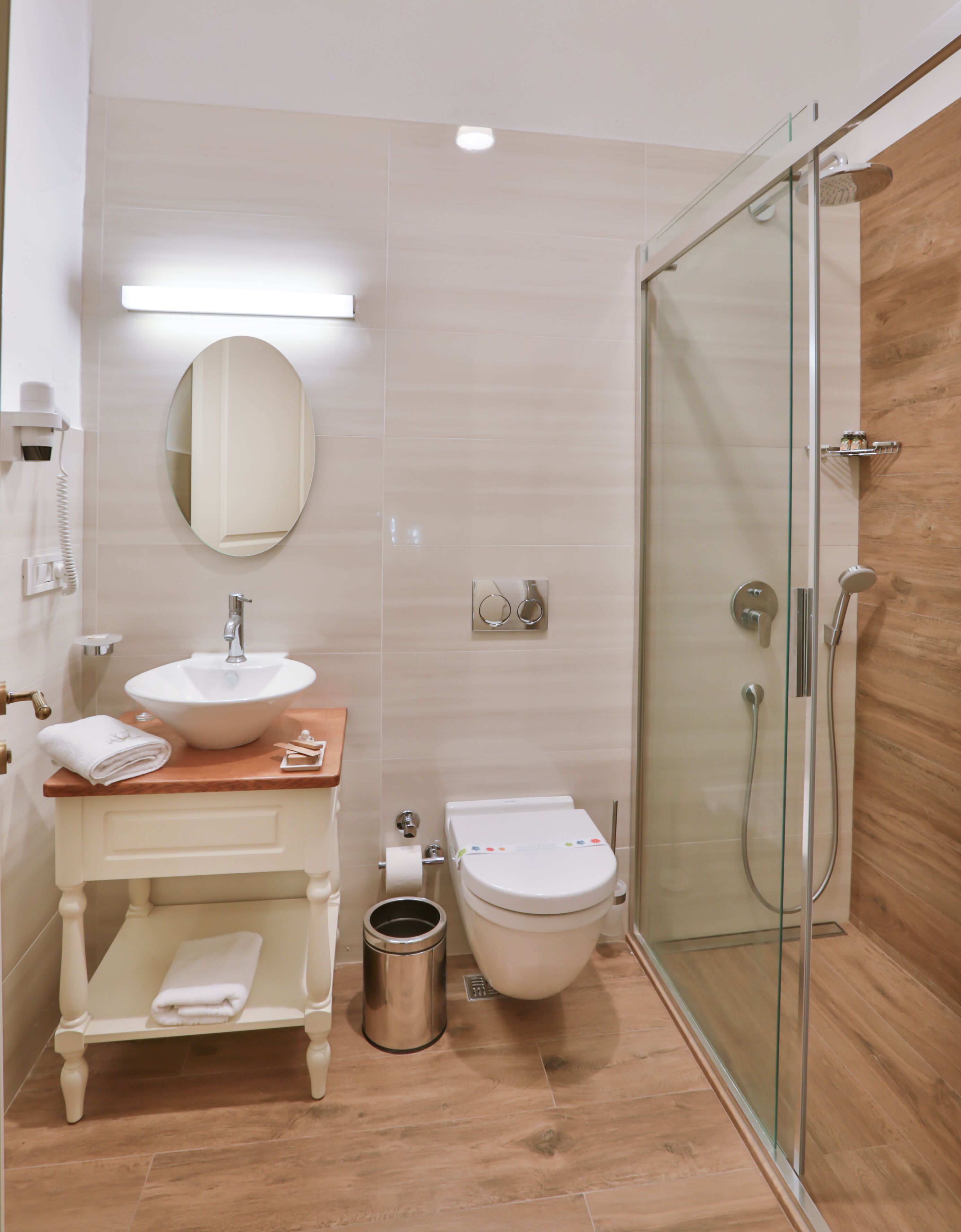 Une salle de bain moderne équipée d’un lavabo, d’un miroir, de toilettes et d’une douche à parois de verre.