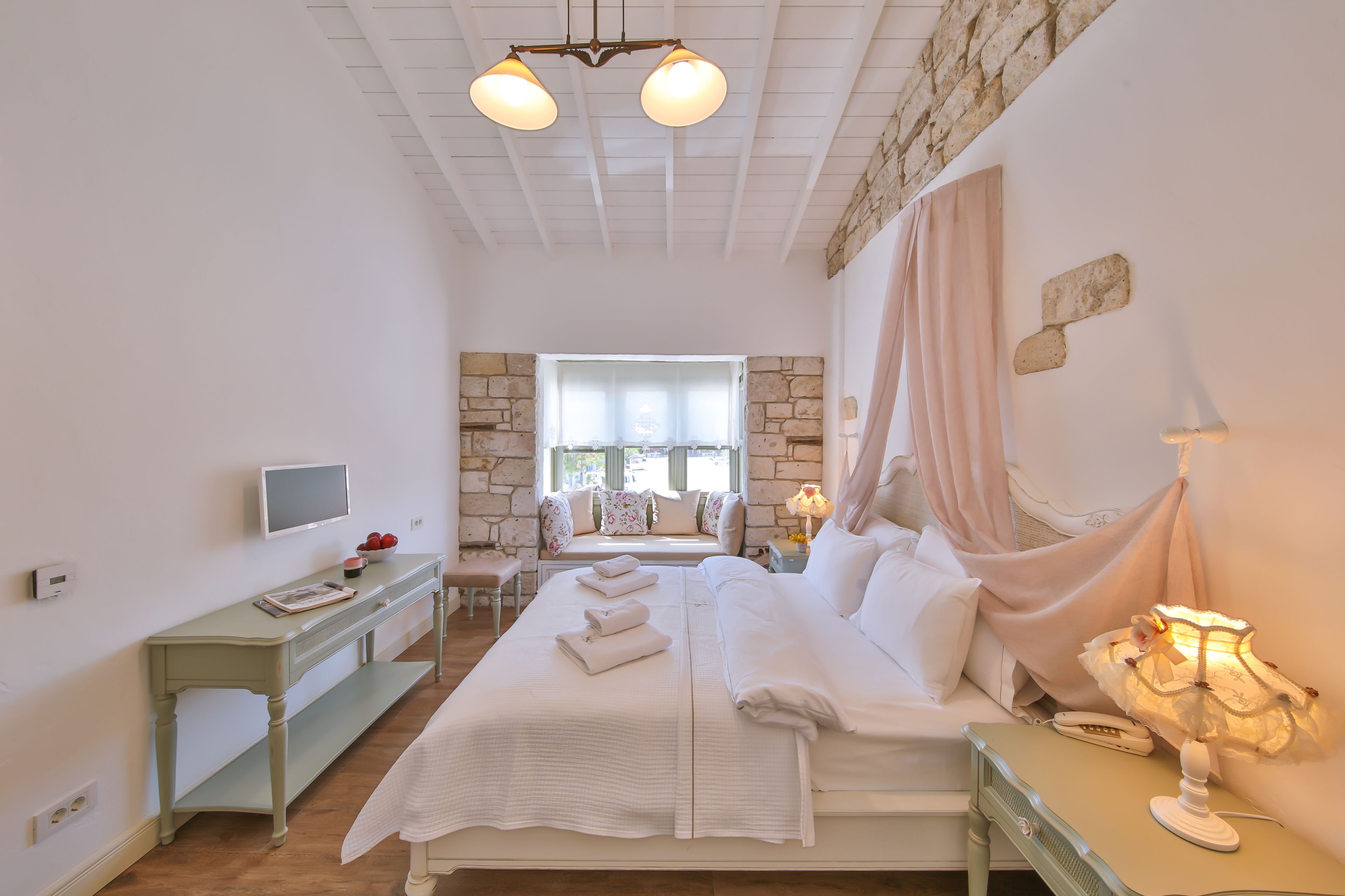 Un dormitorio con cama, mesita de noche, lámpara y vistas al exterior a través de una ventana.