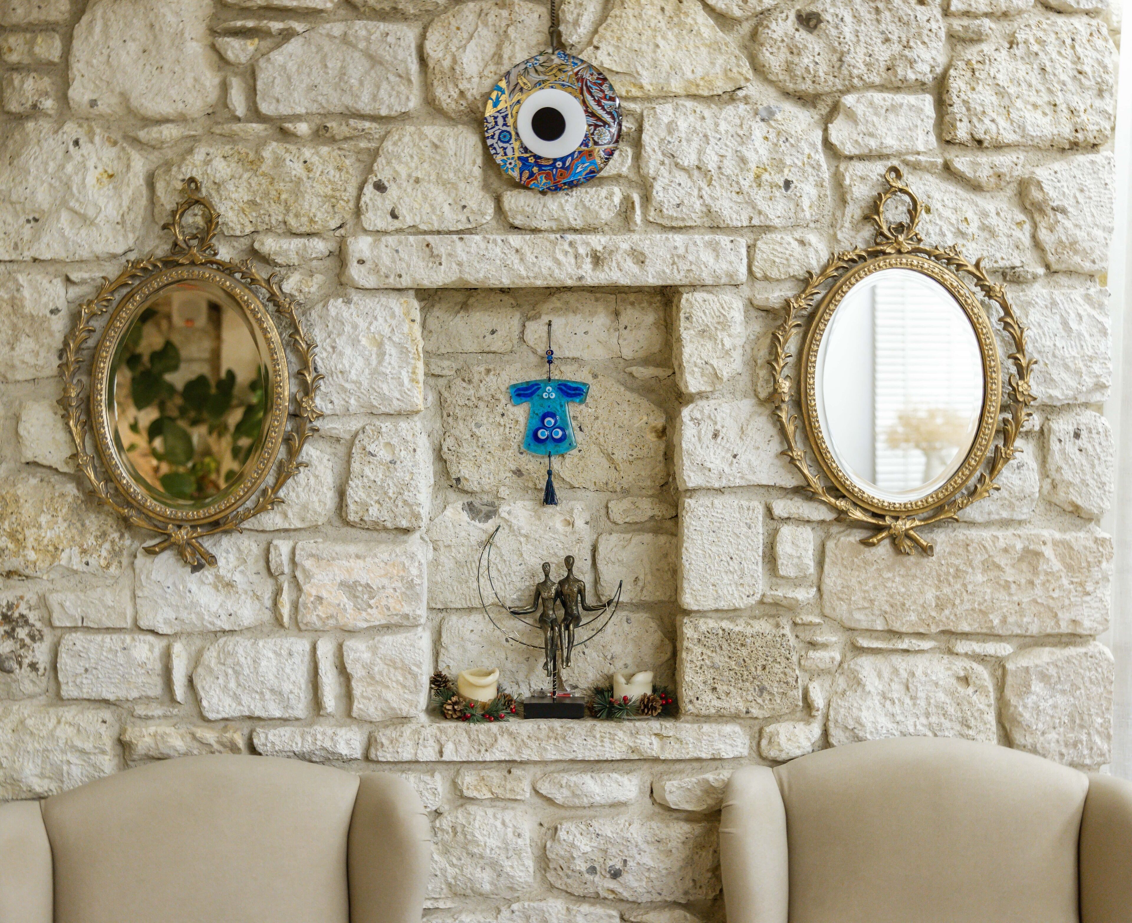 A stone wall with three ornate mirrors and a small blue decorative item.
