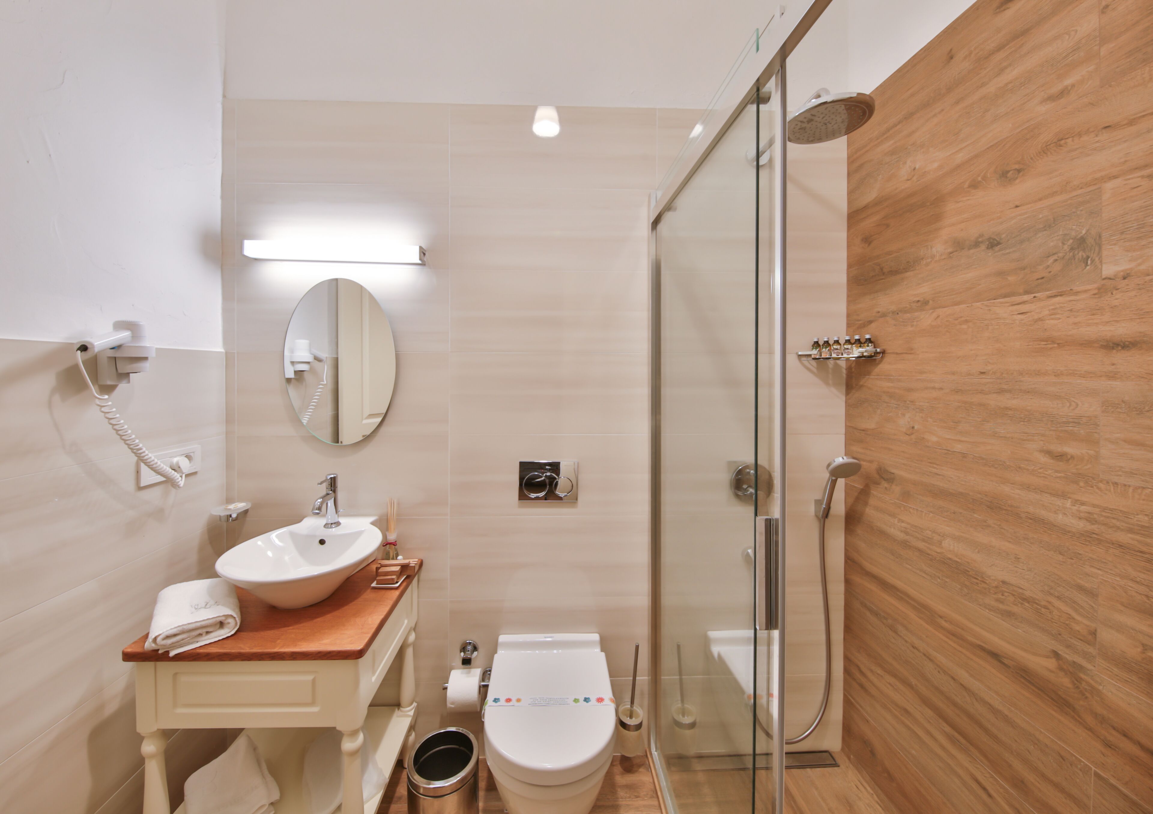 Ein modernes Badezimmer mit einer Duschkabine, einem Holzbadezimmer-Möbelstück, einem Waschbecken und einer Toilette.