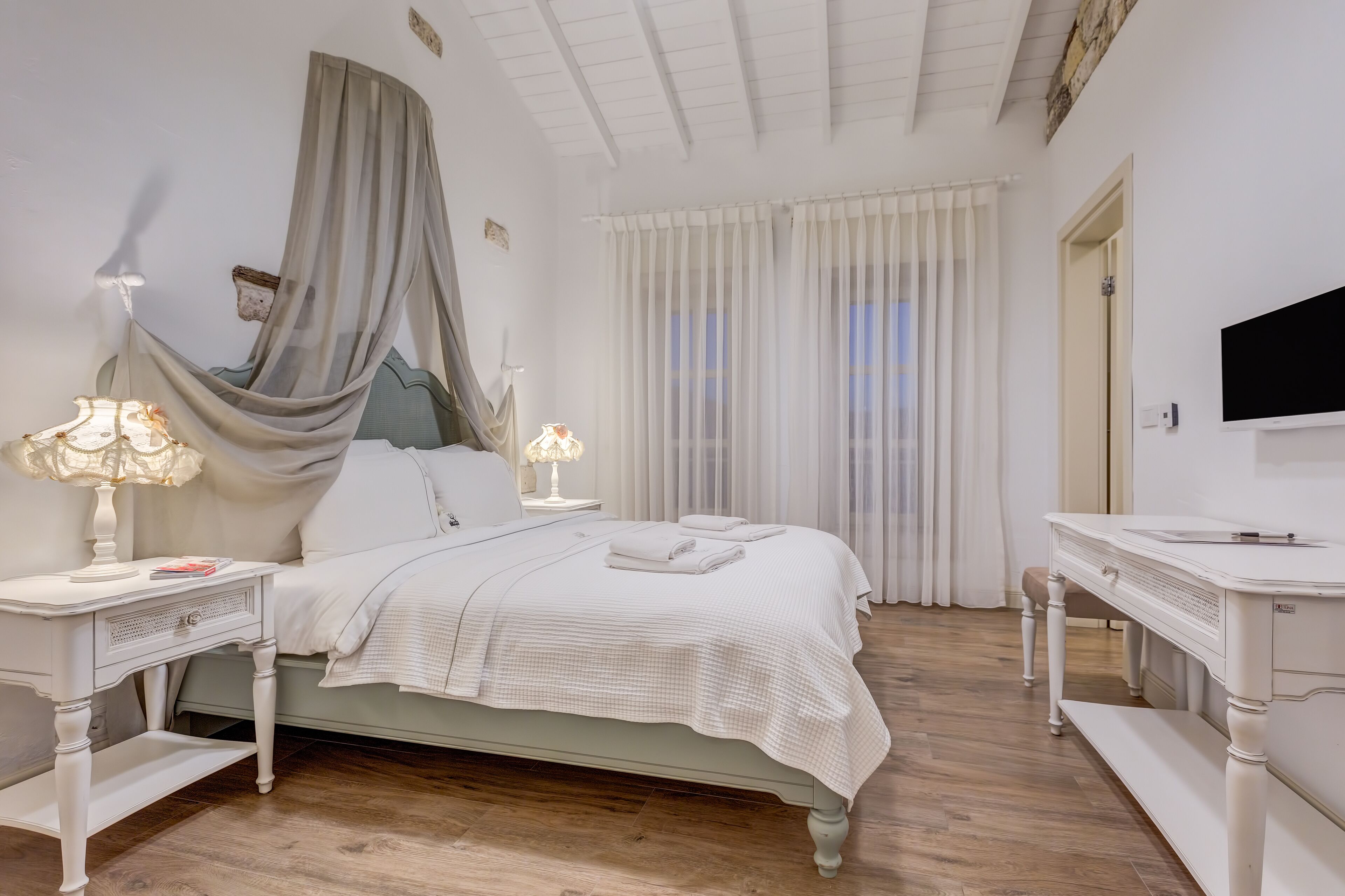 Un dormitorio con cama, mesitas de noche, escritorio y televisor.