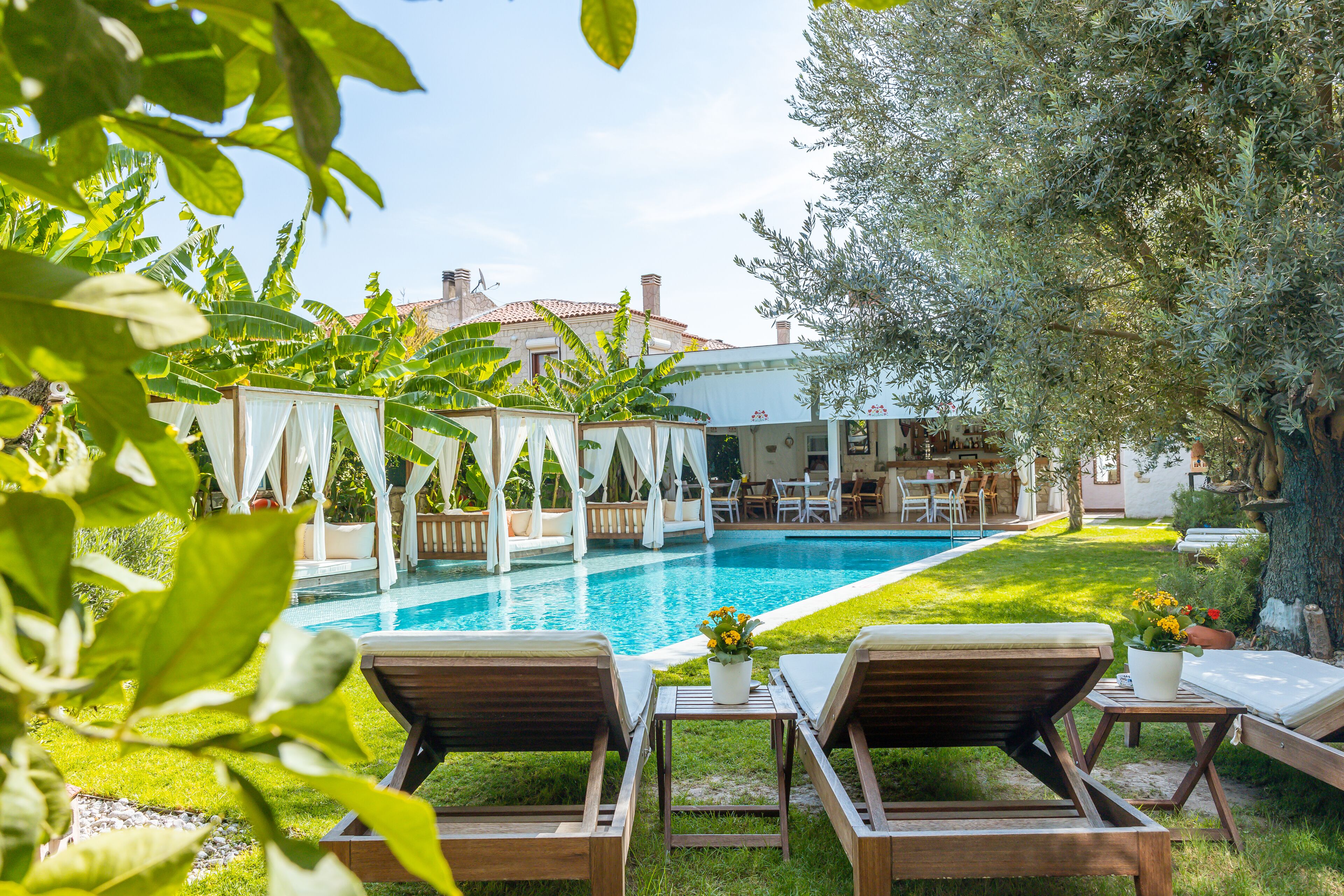 A pool area with lounge chairs, a small table with a potted plant, and a building in the background.