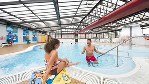 An indoor swimming pool with a glass ceiling, a poolside area with a towel, and a mural on the wall. - Sandy Meadows Lodge Park (Burnham-on-Sea)