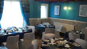 A dining area with round tables set for four, white chairs, and blue tablecloths. - South Dene Hotel (Bridlington)