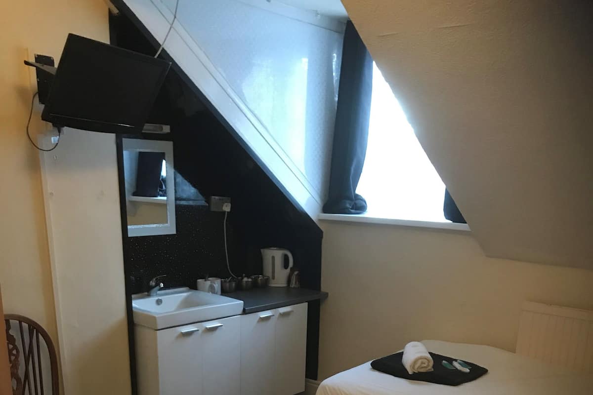 A small hotel room with two beds, a sink, and a mirror.