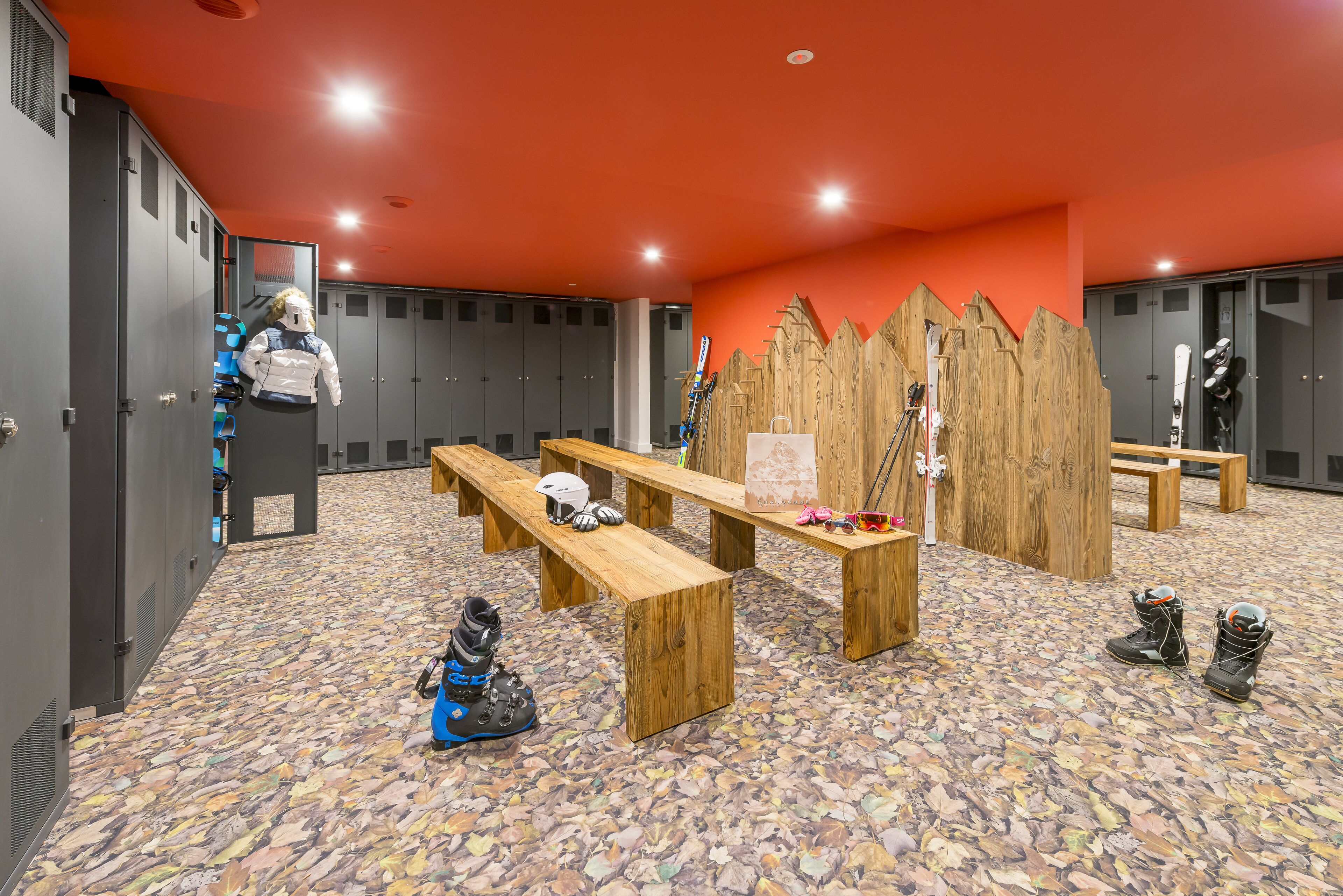 A ski lodge with lockers, wooden benches, and ski equipment.