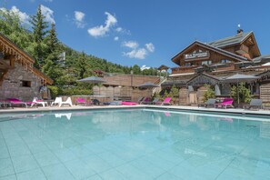 A pool area with lounge chairs and umbrellas, a wooden building with a sign reading "La Roussera Restaurant", and a mountainous backdrop. - Hôtel L'Eterlou (Les Allues)