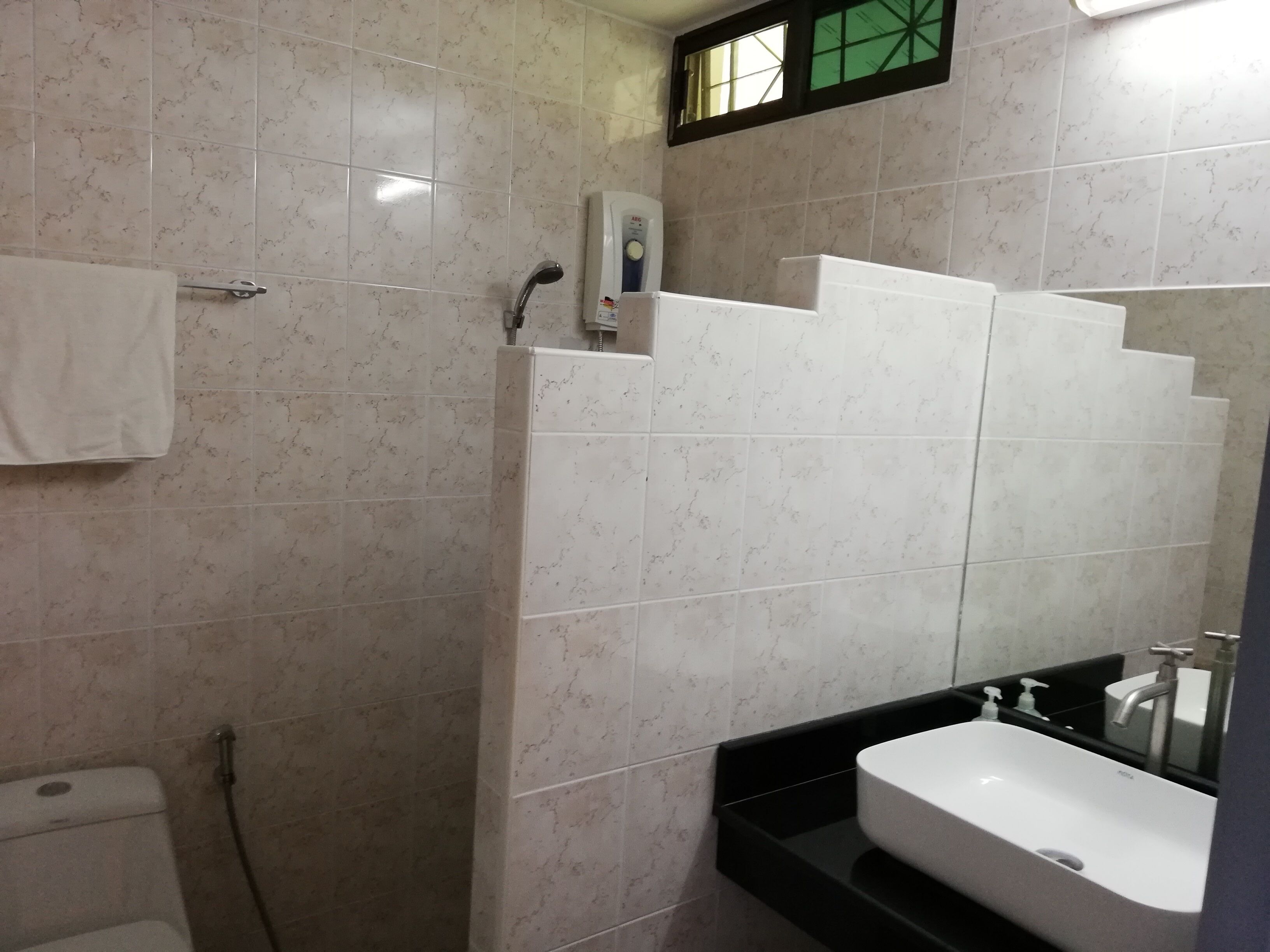 Een badkamer met douche, toilet en wastafel.